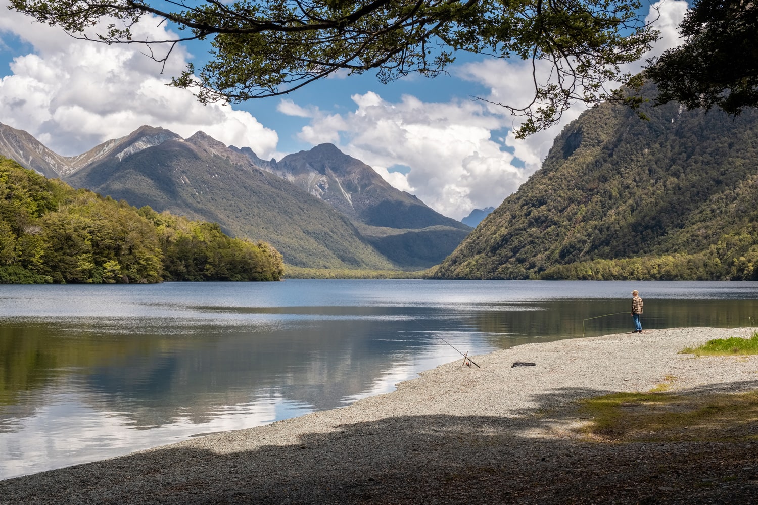 Man fishing on a New Zealand river with mountains in the background